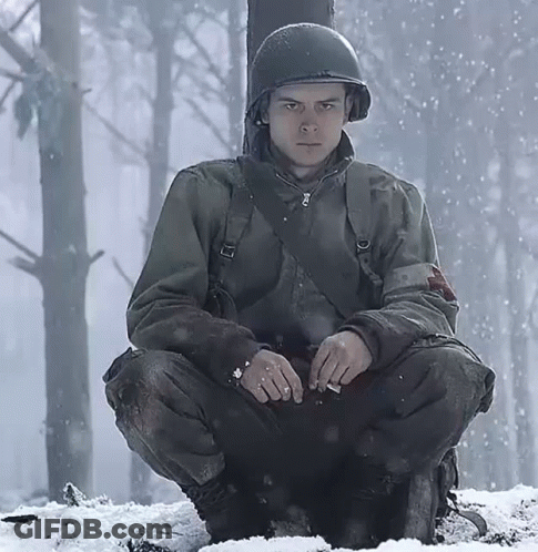 A Soldier In A Helmet Sits In The Snow GIF