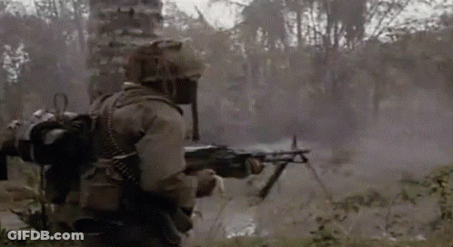 A Soldier Is Holding A Machine Gun In A Field With Trees In The Background GIF