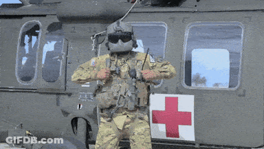 A Soldier Is Standing In Front Of A Helicopter With A Red Cross On The Door GIF