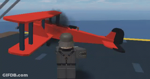 A Soldier Is Standing Next To A Red Airplane On A Runway . GIF