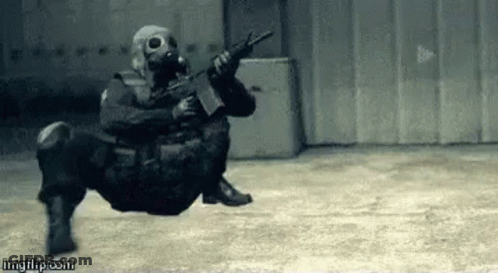 A Soldier Wearing A Gas Mask Is Holding A Gun In A Warehouse . GIF