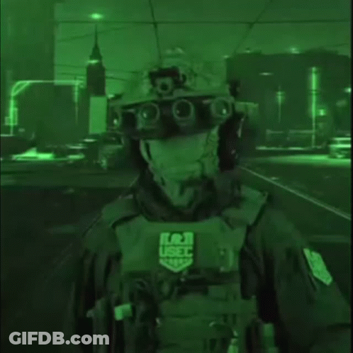 A Soldier Wearing A Helmet And Goggles Is Standing In A Dark Street At Night . GIF