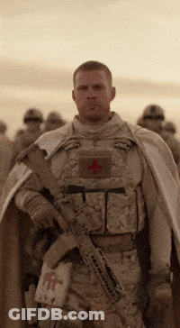 A Soldier With A Red Cross On His Chest Is Holding A Gun GIF