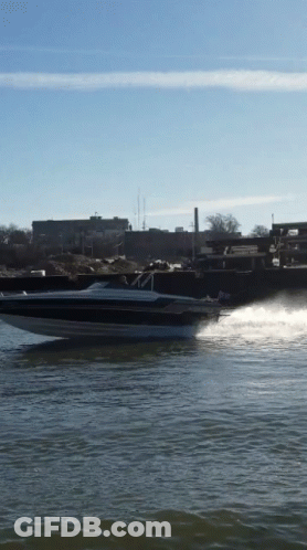 A Speed Boat Is Going Through The Water With A City In The Background GIF