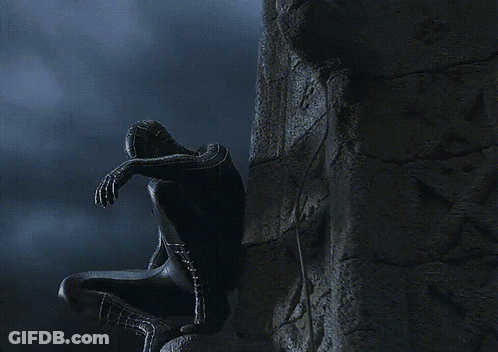A Spider Man In A Black Suit Is Covering His Face GIF