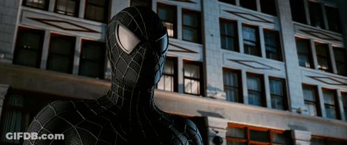 A Spider Man Stands In Front Of A Building GIF