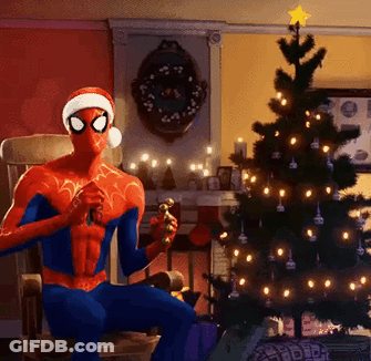 A Spider Man Wearing A Santa Hat Is Sitting In A Chair In Front Of A Christmas Tree GIF