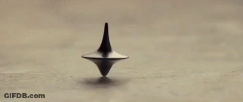 A Spinning Top Is Spinning On A Table In A Black And White Photo . GIF