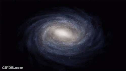 A Spiral Galaxy In The Middle Of A Dark Blue Background GIF