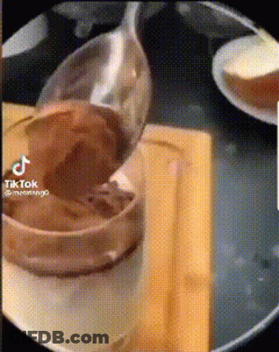 A Spoon Is Sitting On A Plate Next To A Bowl Of Food . GIF