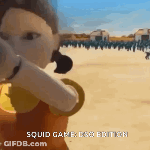 A Squid Game Doll Is Standing In Front Of A Group Of People . GIF
