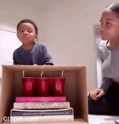 A Stack Of Books Including Oscar De La Renta 'S Legendary World Of Style Sit On A Cardboard Box GIF