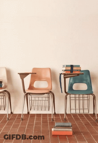 A Stack Of Books Sits On A Brick Floor In Front Of A Wall That Says " Ed " GIF