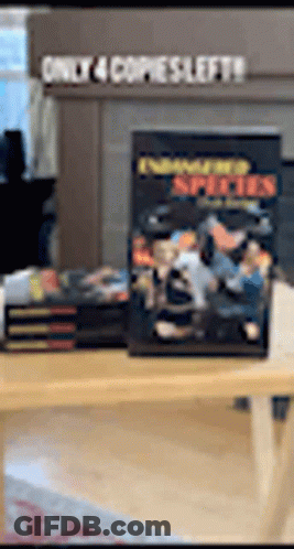A Stack Of Books Sitting On Top Of A Wooden Table With A Sign That Says Only 4 Copies Left . GIF