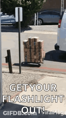 A Stack Of Boxes On A Cart On The Side Of The Road With The Words `` Get Your Flashlight Out '' . GIF