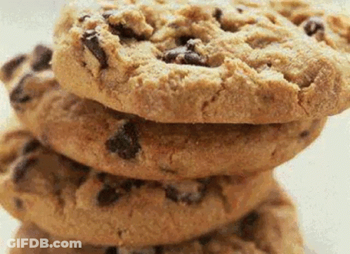 A Stack Of Chocolate Chip Cookies Sitting On Top Of Each Other On A White Plate . GIF