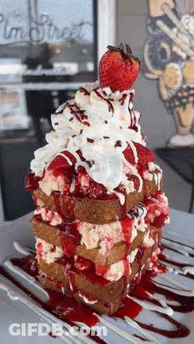 A Stack Of French Toast With Strawberries Whipped Cream And Sauce GIF