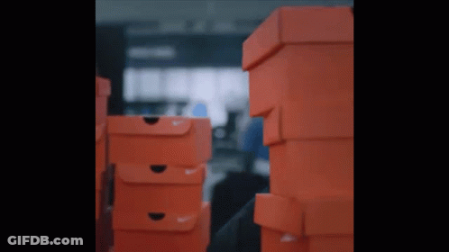 A Stack Of Orange Nike Boxes In A Dark Room GIF