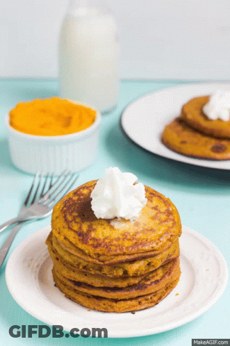 A Stack Of Pancakes On A Plate With Whipped Cream On Top GIF
