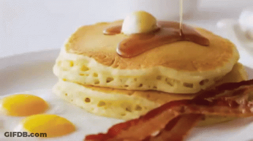 A Stack Of Pancakes With Syrup Being Poured On Them GIF