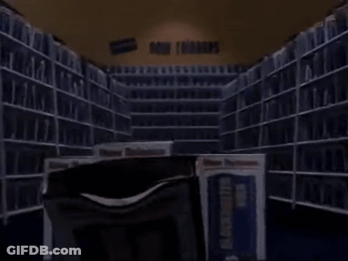 A Stack Of Vhs Tapes In A Library With A Book That Says Buster Video GIF