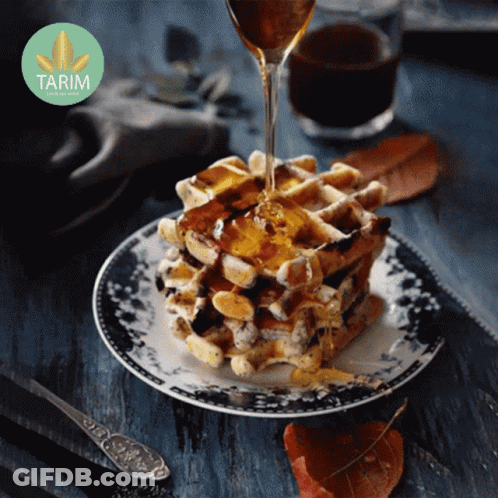 A Stack Of Waffles On A Plate With Syrup Being Poured Over Them With A Tarim Logo In The Background GIF