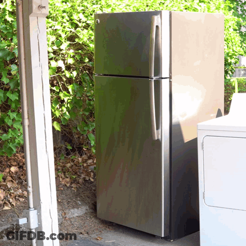 A Stainless Steel Refrigerator Is Sitting Next To A White Washer And Dryer GIF