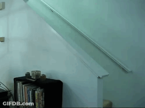A Staircase With A Bookshelf Underneath It And A White Railing GIF