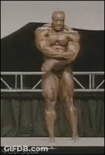 A Statue Of A Bodybuilder Is Standing On A Stage With His Arms Crossed GIF