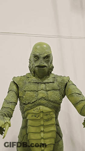 A Statue Of A Creature Has Signatures On It Including Those Of John Carpenter And Peter Fonda GIF