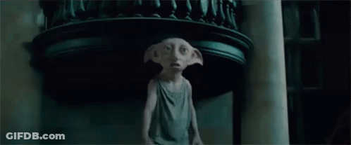 A Statue Of A Dobby From Harry Potter Is Standing In A Dark Room Holding A Cat . GIF