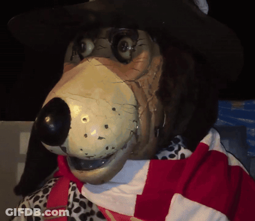 A Statue Of A Dog Wearing A Cowboy Hat And A Scarf GIF