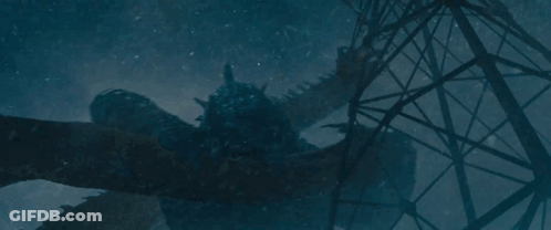 A Statue Of A Dragon Is Laying On The Ground In Front Of A Telephone Pole . GIF