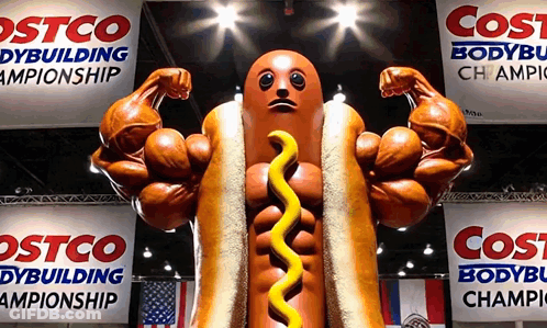 Muscular Hot Dog Statue With Mustard In Front Of Costco GIF