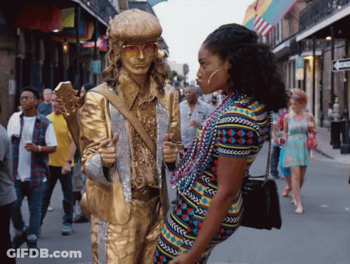 A Statue Of A Man Holding A Guitar Is Standing Next To A Woman Wearing Beads GIF