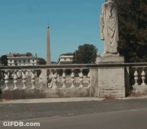 A Statue Of A Man In A Robe Is On A Bridge GIF