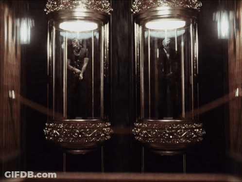 A Statue Of A Man In A Suit Is Displayed In A Glass Case GIF