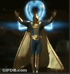 A Statue Of A Man In A Superhero Costume With His Arms Outstretched GIF