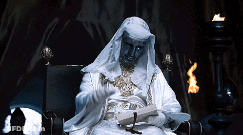A Statue Of A Man In A White Robe Is Reading A Book GIF