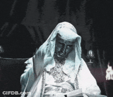 A Statue Of A Man In A White Robe Waves His Hand GIF