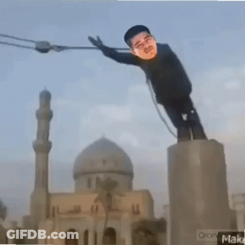 A Statue Of A Man Is Hanging From A Rope In Front Of A Mosque GIF