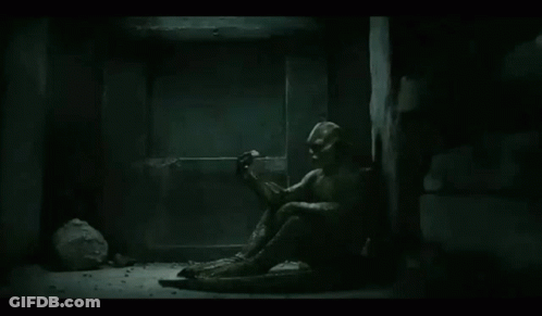 A Statue Of A Man Is Sitting On The Floor In A Dark Room . GIF