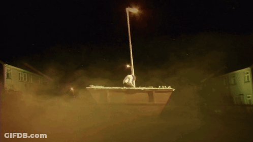 A Statue Of A Man Standing On Top Of A Dumpster GIF