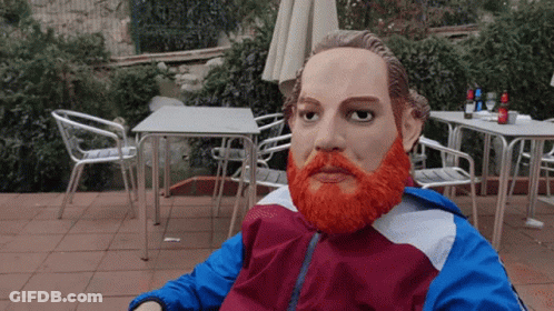A Statue Of A Man With An Orange Beard Is Sitting In A Chair GIF