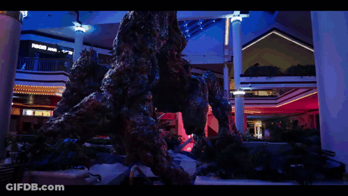 A Statue Of A Monster In A Mall With A Sign That Says ' A & R ' On It GIF