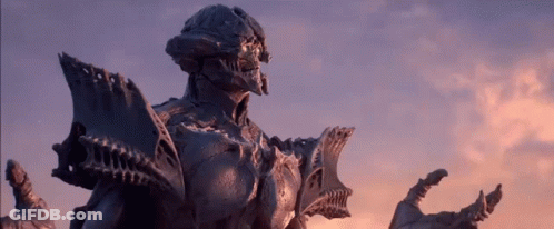 A Statue Of A Monster Is Standing In Front Of A Sunset Sky GIF