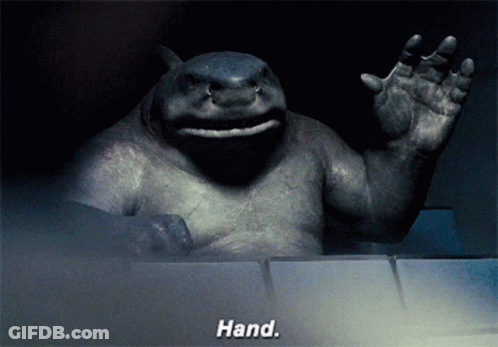 A Statue Of A Shark Waving With The Words Hand Behind It GIF