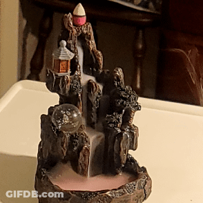 A Statue Of A Waterfall Is Sitting On A White Table GIF