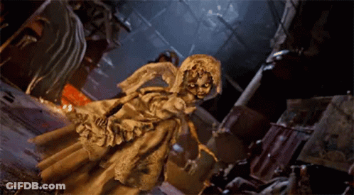 A Statue Of A Woman In A White Dress And Veil Is Standing In A Dark Room . GIF