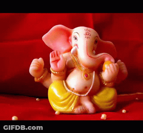 A Statue Of Ganesha Is Sitting On A Red Surface With Pearls Around It GIF